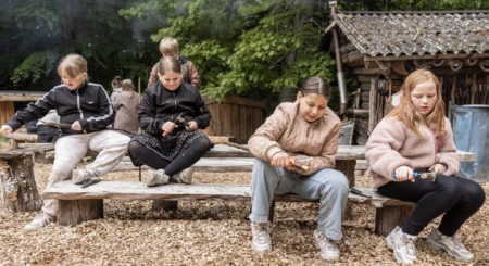 Fire børn snitter pinde udendørs ved Julemærkehjemmet Hobro