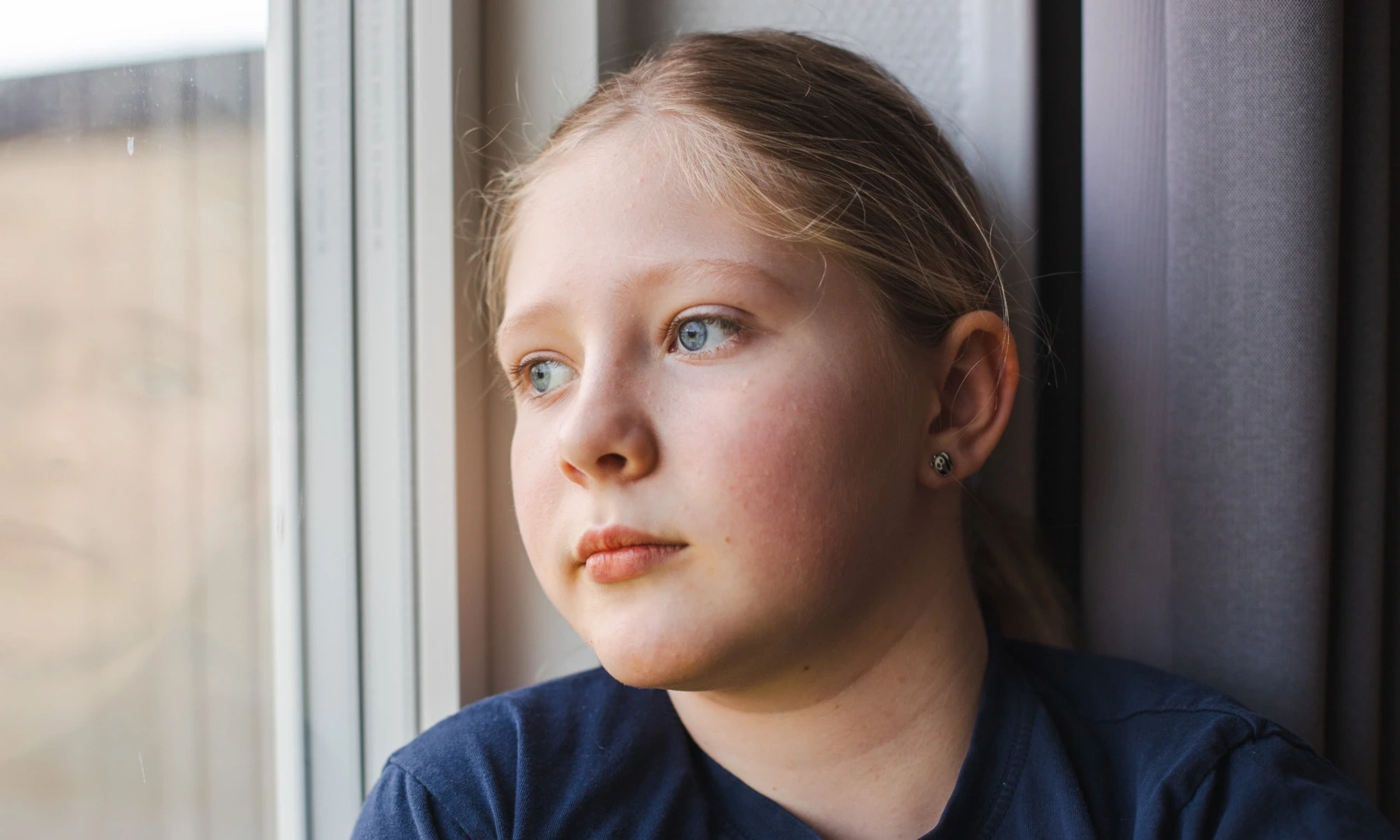 Barn på Julemaerkehjem. Hun hedder Thea. Paa billedet kigger hun ud af et vindue